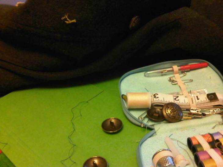 Four brass-a-like buttons and the coat with torn threads where they belong; a small sewing kit.