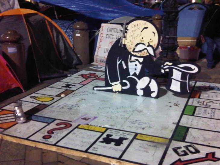 A large monopoly board with a silver boot (an actual boot) and a life sized cardboard cut out of Mr Moneybags looking unhappy and broke.